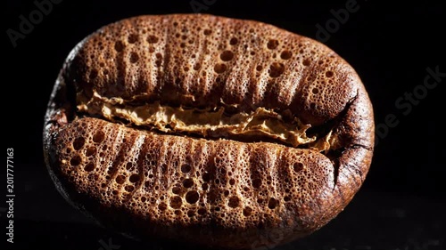 Extreme closeup of a roasted coffee bean with intricate texture and deep brown color, isolated on a dark background, showcasing aroma and caffeine energy
