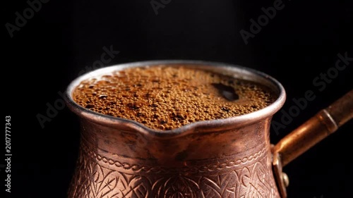 Close up of steaming freshly brewed coffee in a decorative copper cezve, bubbling and frothing, dark background, rich aroma, morning ritual, hot beverage
