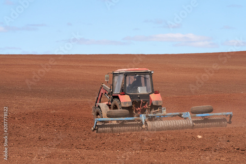 Spring sowing campaign. A tractor uses a trailed roller to bury the seeds in the soil.