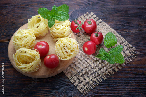 Pasta, tomatoes and mint lie on a wooden table