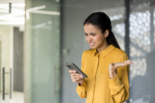 Billede på lærred Woman experiencing frustration and bad news on smartphone in office