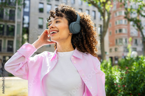 Hispanic woman enjoying music on headphones outdoors