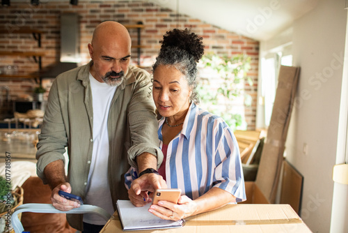 Mature couple planning home move with smartphone in kitchen