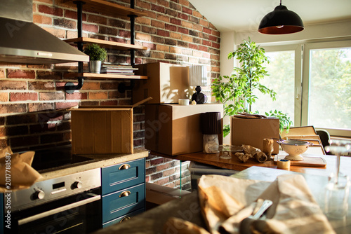 Household moving boxes in sunny brick kitchen