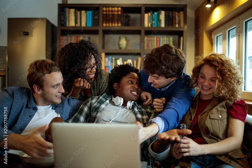 Fototapeta premium Diverse friends watching video on laptop at home