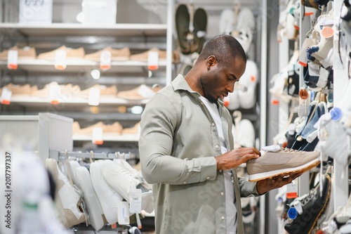 Obraz na plátně Stylish man choosing sneakers in a shoe store