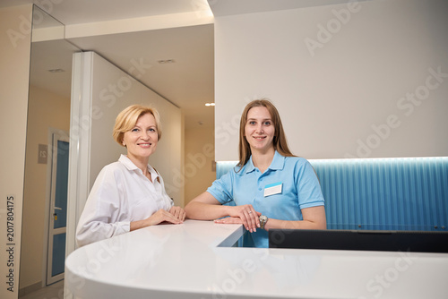 Two women smiling at reception desk in modern clinic