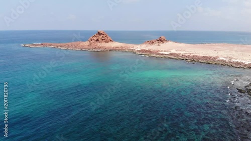 Captivating aerial video from a single point on Socotra Island, showcasing gentle waves lapping against unique rock formations in the clear blue ocean