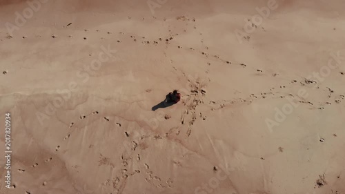 Panoramic aerial video of a person meditating peacefully on a vast, sandy beach by the ocean, perfect for themes of solitude, wellness, and serene escapes