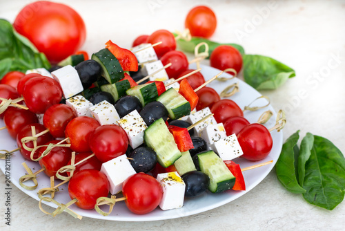 Salami appetizer skewers with pickles mozzarella and basil on white plate
