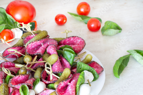 Gourmet salami skewers with mozzarella basil and pickles party snack concept