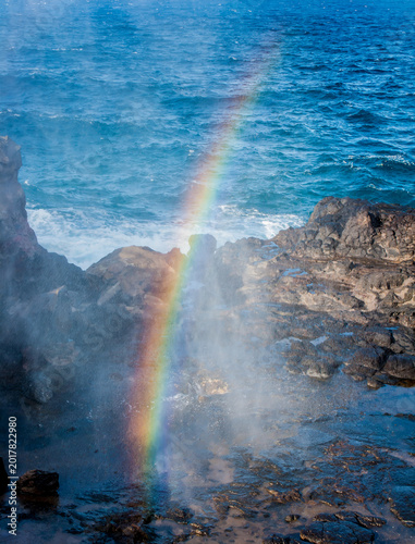 A rainbow forms in the mist from the Nakalele blow hole on Maui Hawaii