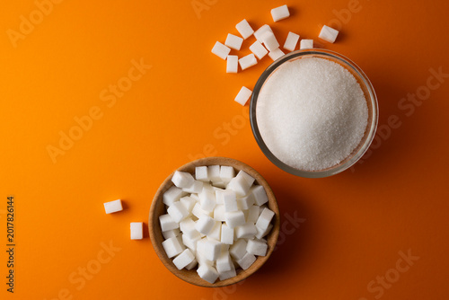 White crystal sugar and sugar cubes on a colored background, space for text