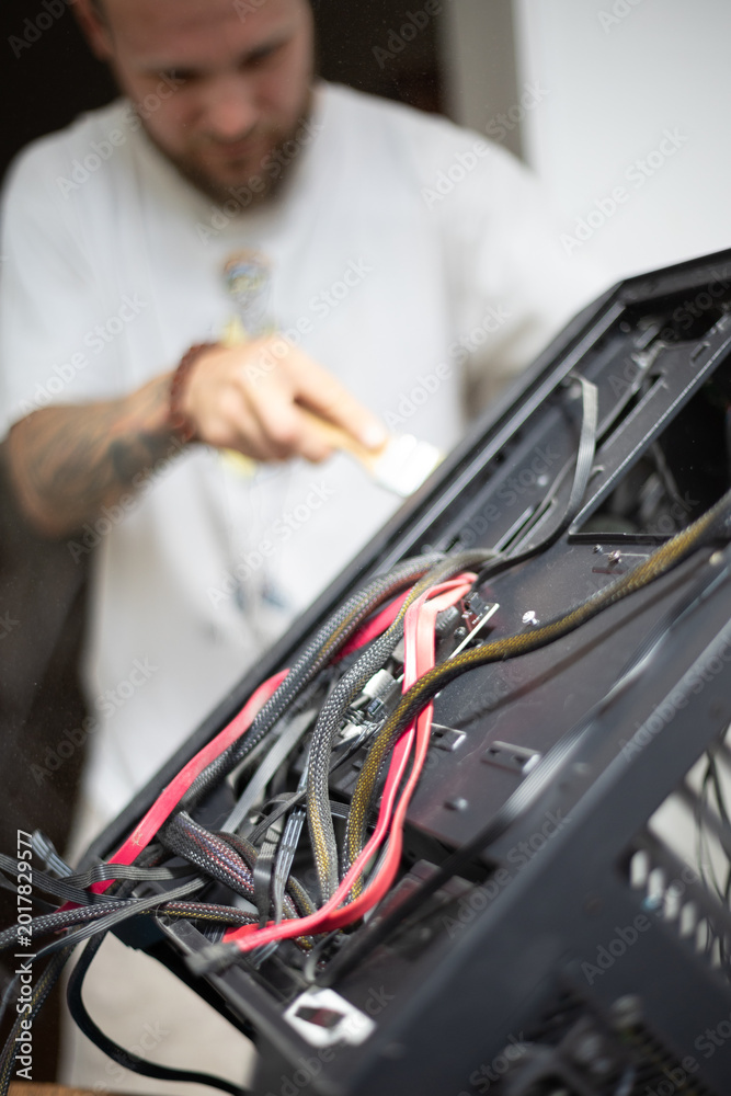 Fototapeta premium Person repairs computer case with wires and tools while focused on task in a well-lit room
