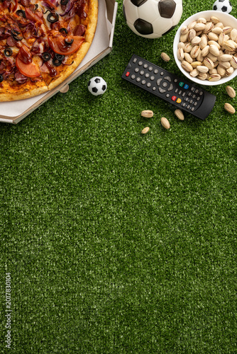 Bild auf Leinwand Football championship viewing with pizza, pistachios and remote on vertical gras