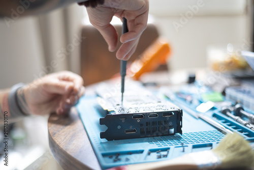 Εκτύπωση καμβά Person working on a computer part on a table with tools and materials in a room