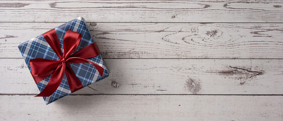 Happy Father's Day blue plaid gift with red ribbon on banner wooden background