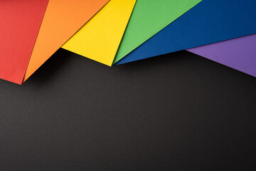Rainbow paper layers on black background representing Pride Month colors and minimalist design