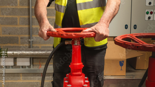 Bild auf Leinwand Engineer checking water supply pump on red valve for sprinkler fire protection system