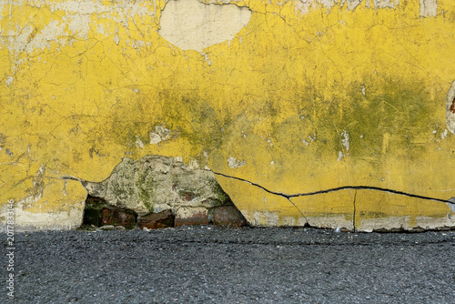 An old, cracked yellow wall with remnants of time