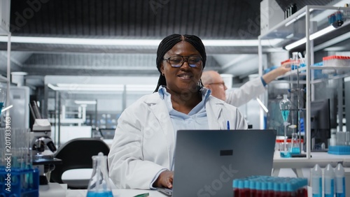 Foto Portrait of cheerful scientist using laptop software in laboratory, driving treatment discovery