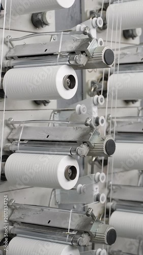 Industrial textile machine spinning white yarn spools