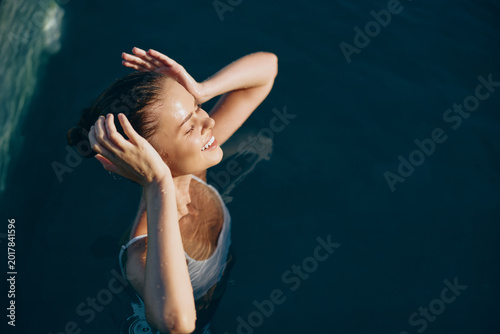 Fotografía Joyful woman floating in sunlit water, smiling with eyes closed, relaxed posture