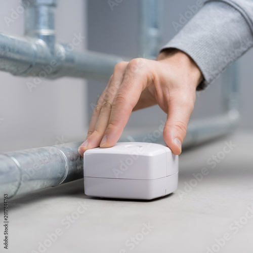 Hand installing smart home water leak sensor
