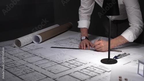 Fotografie Architect hands drawing blueprint for new building design, working on infrastructure project plans at night
