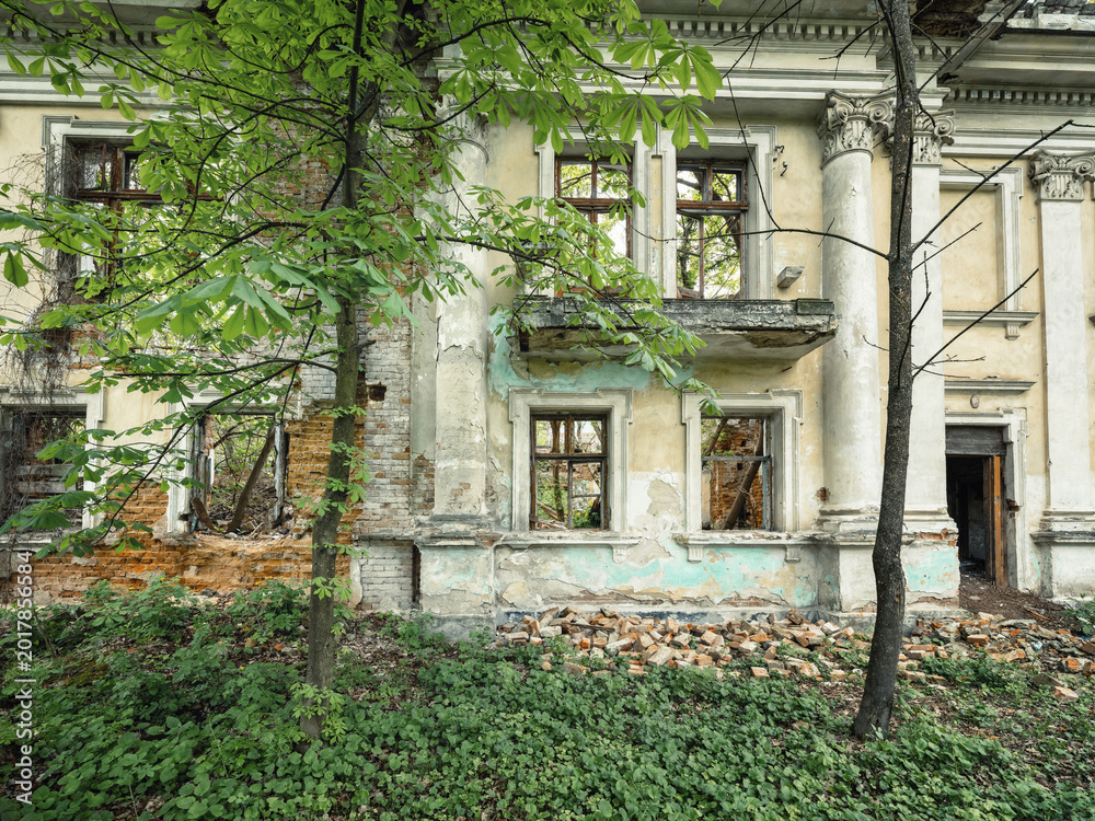 Fototapeta premium view to facade with balcony of old abandoned palace with spring trees