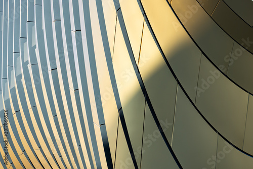 Abstract architectural detail of curved metallic panels reflecting light, showcasing modern design elements in a contemporary building structure