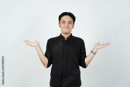 Smiling young Asian man shrugging or presenting options with both hands on white background