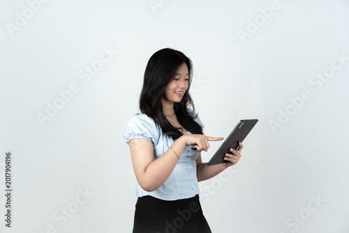 Happy young woman presenting digital tablet content against white studio background