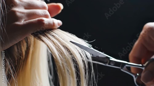 Hairstylist trimming blonde hair with scissors