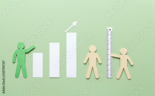 Paper cutouts show growth measurement and human progress against a