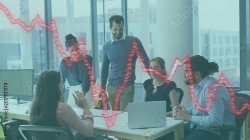 Standing man tapping laptop, leading team reviewing market data while red graph tracking trends