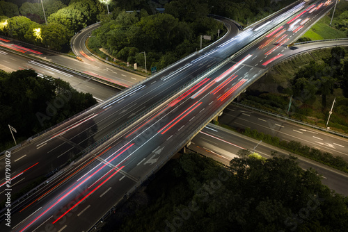 Aerial view of symmetrical highway interchange at night with vibrant light trails