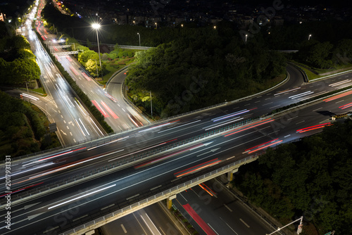 Aerial view of symmetrical highway interchange at night with vibrant light trails