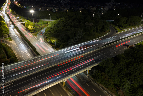 Aerial view of symmetrical highway interchange at night with vibrant light trails