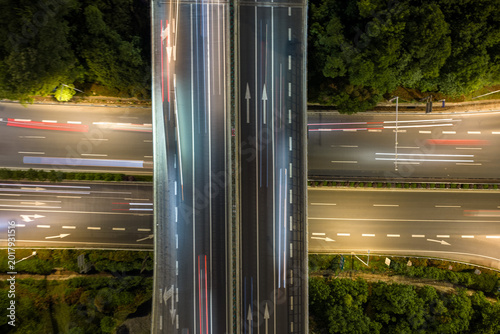 Aerial view of symmetrical highway interchange at night with vibrant light trails