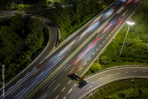 Aerial view of symmetrical highway interchange at night with vibrant light trails