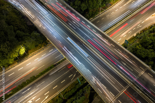 Aerial view of symmetrical highway interchange at night with vibrant light trails