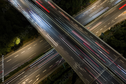 Aerial view of symmetrical highway interchange at night with vibrant light trails