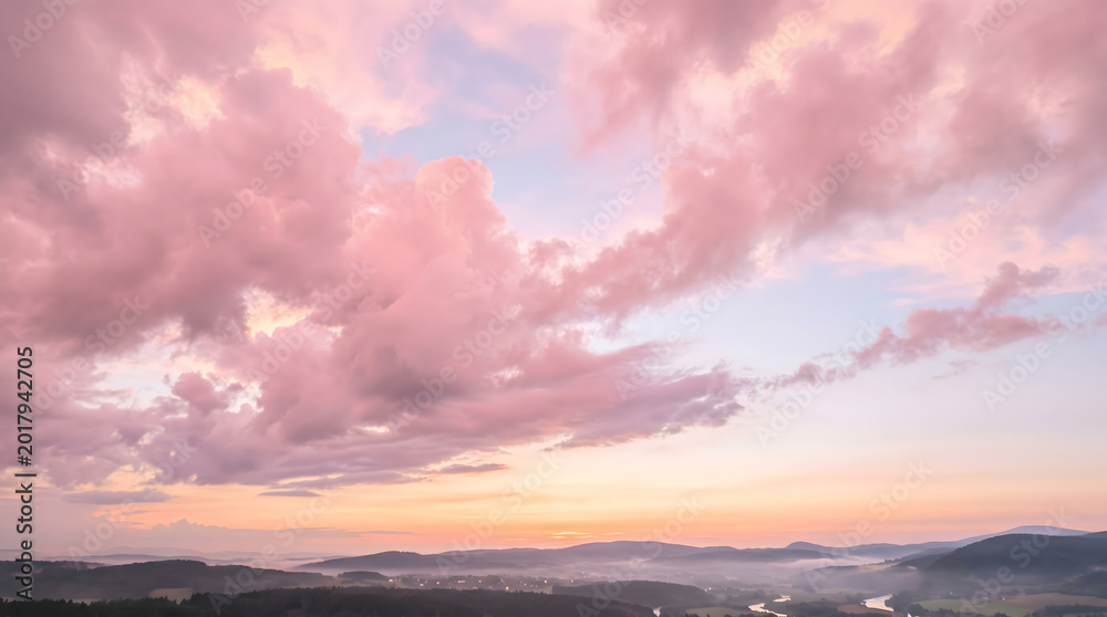 Fototapeta premium Beautiful pink clouds at sunset over a misty landscape, creating a serene and breathtaking natural panorama