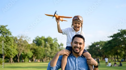 Joyful father carrying his son on shoulders in a sunlit park, boy plays with a toy airplane, embodying childhood dreams and family happiness