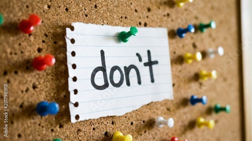 Note with word dont pinned on corkboard with colorful thumbtacks. Simple paper message implies prohibition or a negative instruction for office or school use. Notice Board Communication & Restrictions