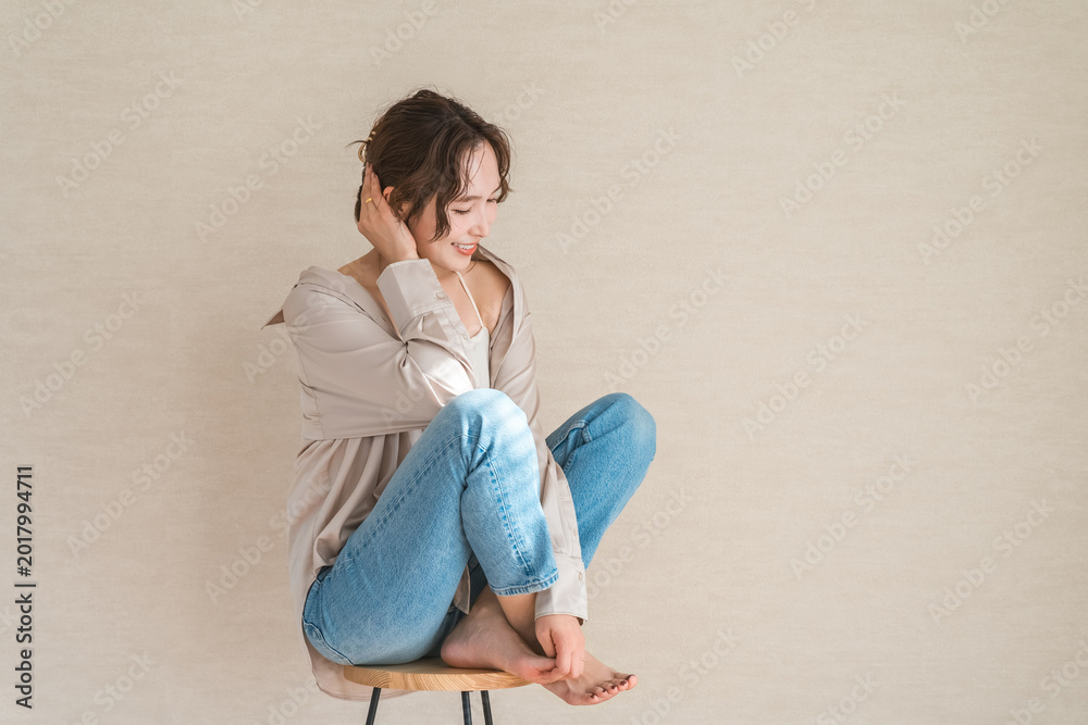 Fototapeta premium A female model in denim clothing sitting on a high chair.