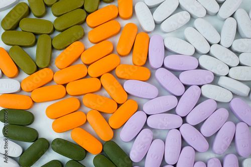 Schilderij op canvas Multicolor oblong tablets arranged in groups on a white background in a flat lay composition