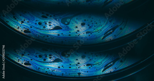 Dye water. Rainbow pollution. Blur blue purple green colorful chemical round oil water liquid leak on abstract dark black background.