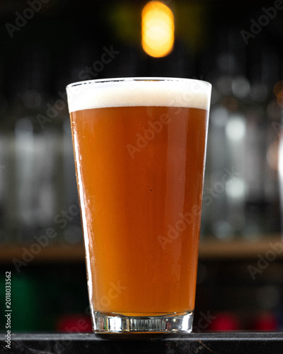 Foto Golden beer fills a pint glass